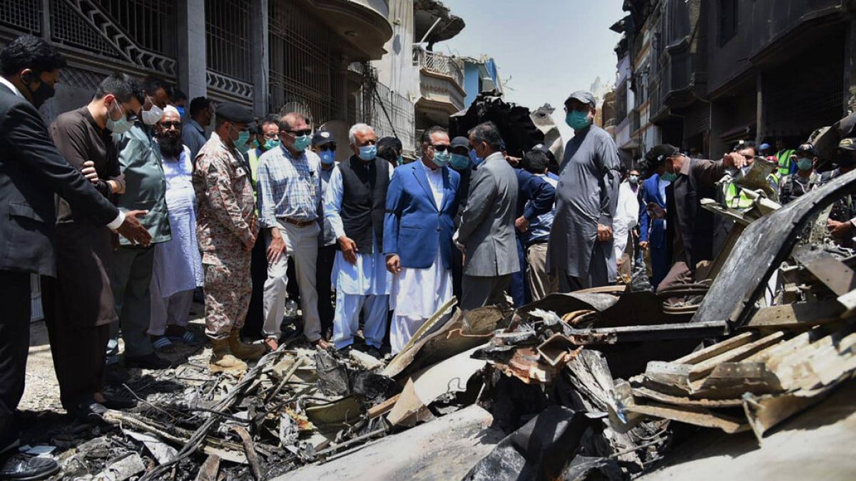 Provincial governor Imran Ismail, center, in blue coat, and Pakistan's aviation minister Ghulam Sarwar, center in black waistcoat, visit the site of Friday's plane crash