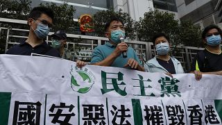 أعضاء الحزب الديمقراطي يحملون لافتات خلال احتجاج أمام مكتب الحكومة المركزية الصينية في هونغ كونغ.