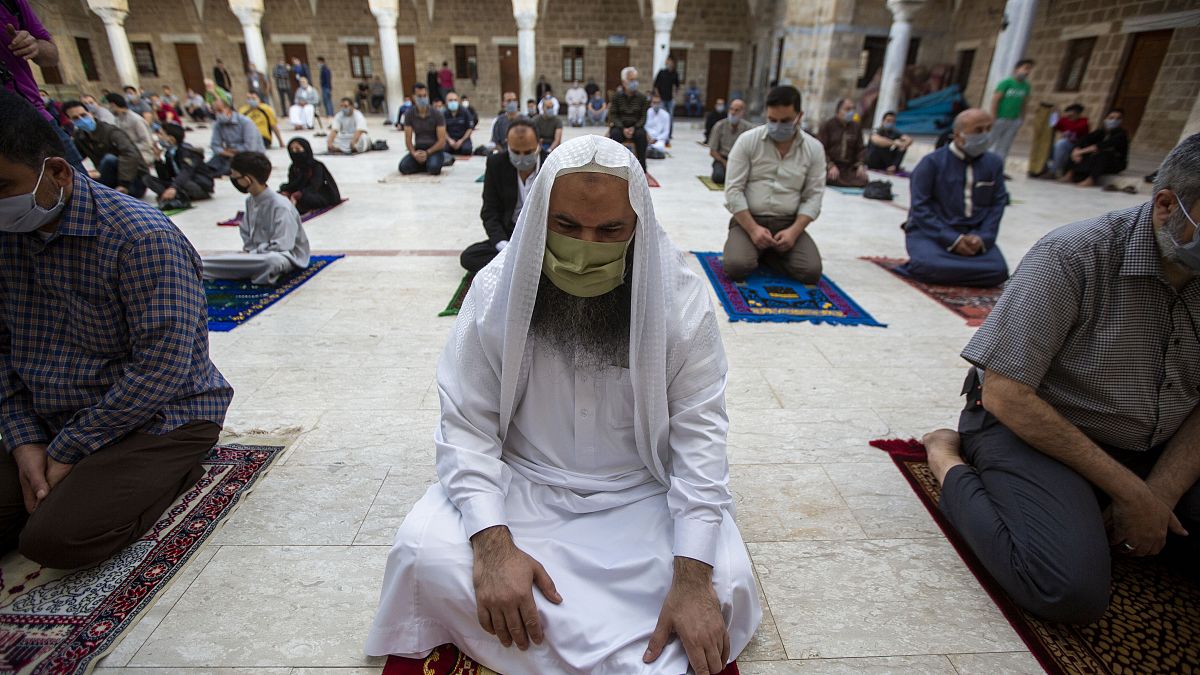 Musulmanes con máscaras faciales asisten a las oraciones de Eid al-Fitr fuera de una mezquita en la ciudad de Gaza, el 24 de mayo de 2020.