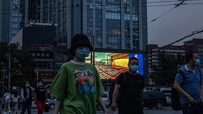 Des personnes marchent dans la rue alors qu'un écran géant diffuse des images du congrès national, Pékin le 22 mai 2020