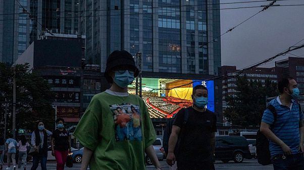 Des personnes marchent dans la rue alors qu'un écran géant diffuse des images du congrès national, Pékin le 22 mai 2020 Des personnes marchent dans la rue alors qu'un écran géant diffuse des images du congrès national, Pékin le 22 mai 2020