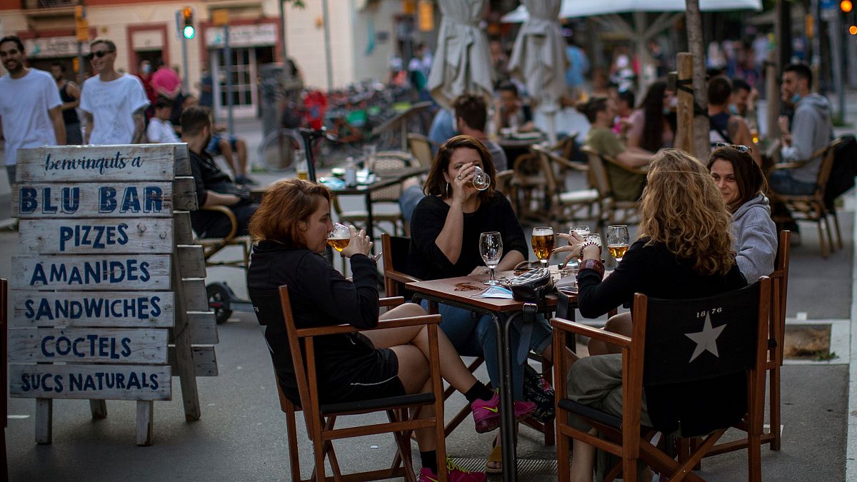 People drink as they sit on a terrace in Barcelona on Monday, May 25