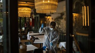 A worker cleans a restaurant ahead of the opening on Monday, May 25, 2020 in Barcelona, Spain.