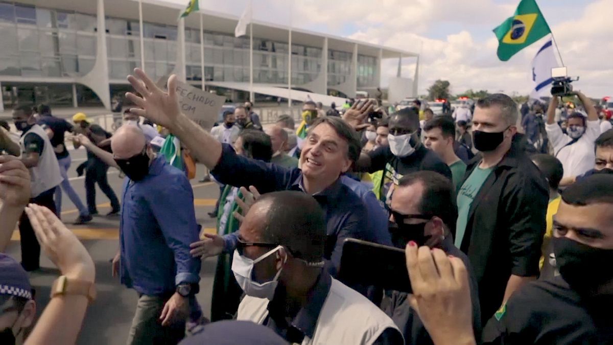 Despite virus surge, President Jair Bolsonaro greets his supporters without a face mask.