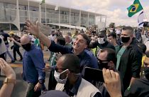 Despite virus surge, President Jair Bolsonaro greets his supporters without a face mask.