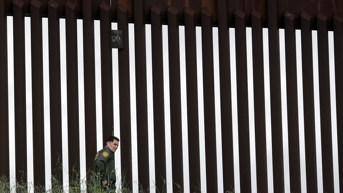 A border patrol agent walks along a border wall separating Tijuana, Mexico, from San Diego, Wednesday, March 18, 2020, in San Diego
