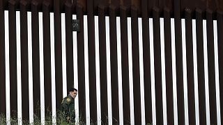 A border patrol agent walks along a border wall separating Tijuana, Mexico, from San Diego, Wednesday, March 18, 2020, in San Diego