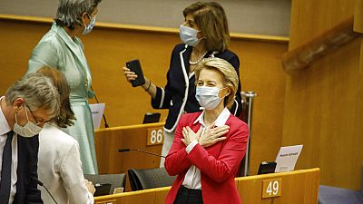 European Commission President Ursula von der Leyen, right, gestures hello to an MEP prior to addressing the European Parliament plenary in Brussels, Wednesday, May 27, 2020. 