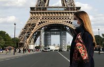 A woman wearing protective face mask walks next to the Eiffel Tower in Paris