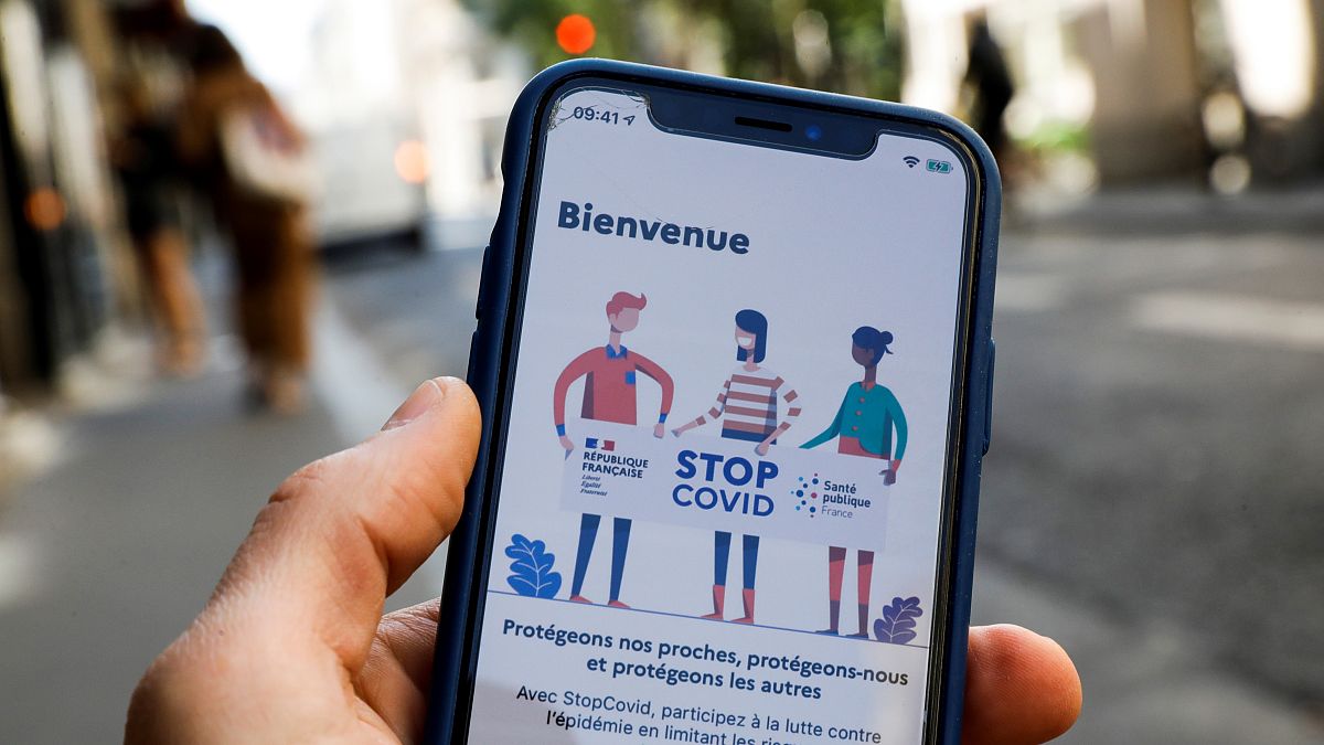 A man holds a mobile phone displaying a screenshot of the tracking application StopCovid developed by the French government.