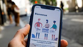 A man holds a mobile phone displaying a screenshot of the tracking application StopCovid developed by the French government.