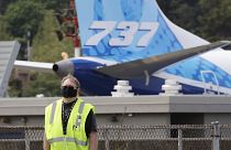 A masked worker walks in view of a 737 jet at a Boeing airplane manufacturing plant