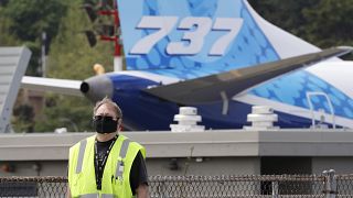A masked worker walks in view of a 737 jet at a Boeing airplane manufacturing plant