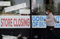 A man looks at signs of a closed store due to COVID-19 in Niles, Ill., Thursday, May 21, 2020.