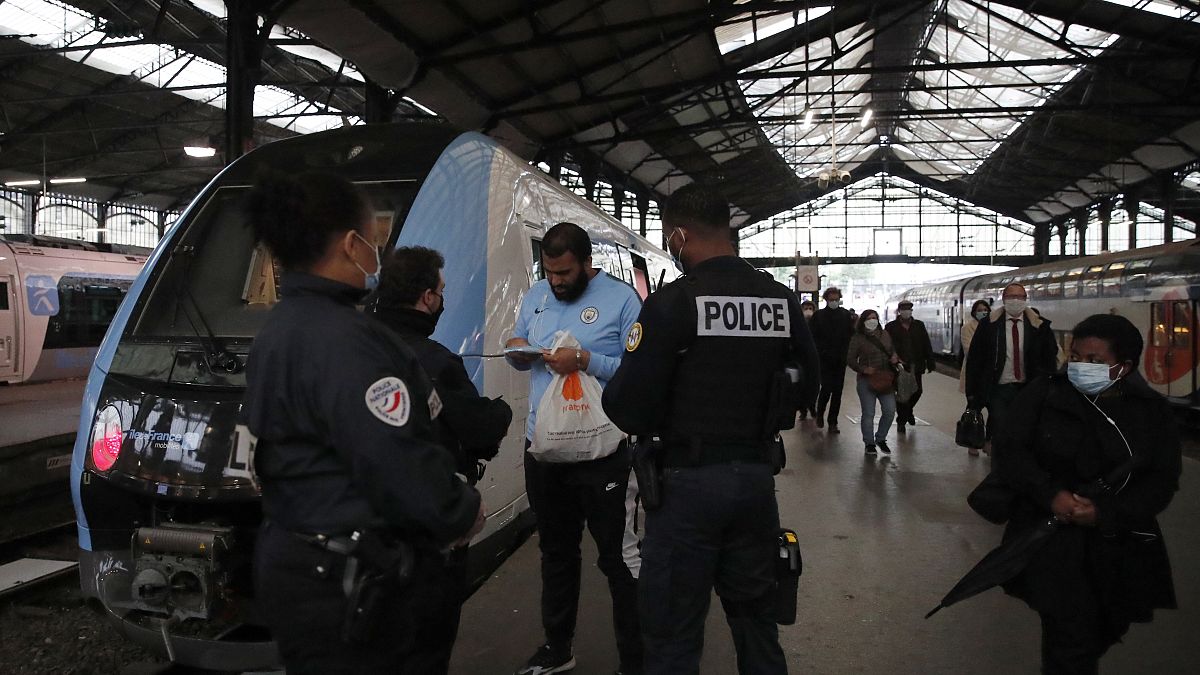 Police officers ask a man to put on his compulsory mask at the Saint Lazare train station