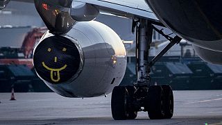 The engine of a Lufthansa aircraft is covered with a blanket that shows a face with tongue out at the airport in Frankfurt, Germany