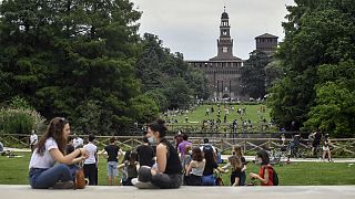 People enjoy sitting in a park in central Milan, northern Italy