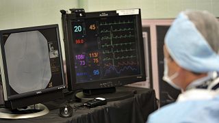 A doctor watches a monitor as he inserts a stent into an artery during a cardiology simulation