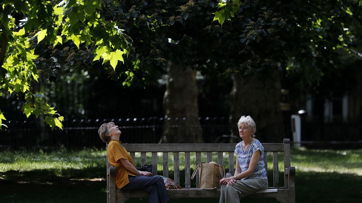امراتان تجلسان على مقعد خشبي في إحدى حدائق لندن - 2020/05/26