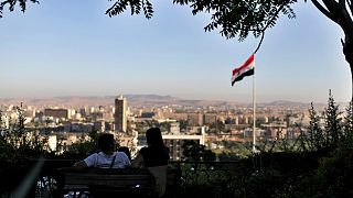 شاب ورفيقته يجلسان في حديقة عمومية مطلة على العاصمة السورية دمشق - 2019/07/24