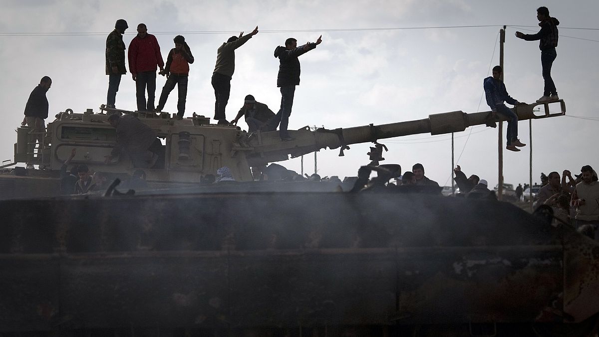 Libya'nın Bingazi kentinde tahrip edilen bir tankın üzerinde kutlama yapan halk (arşiv) 