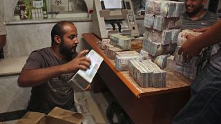مواطن ليبي يعد رزم من الأموال في طرابلس