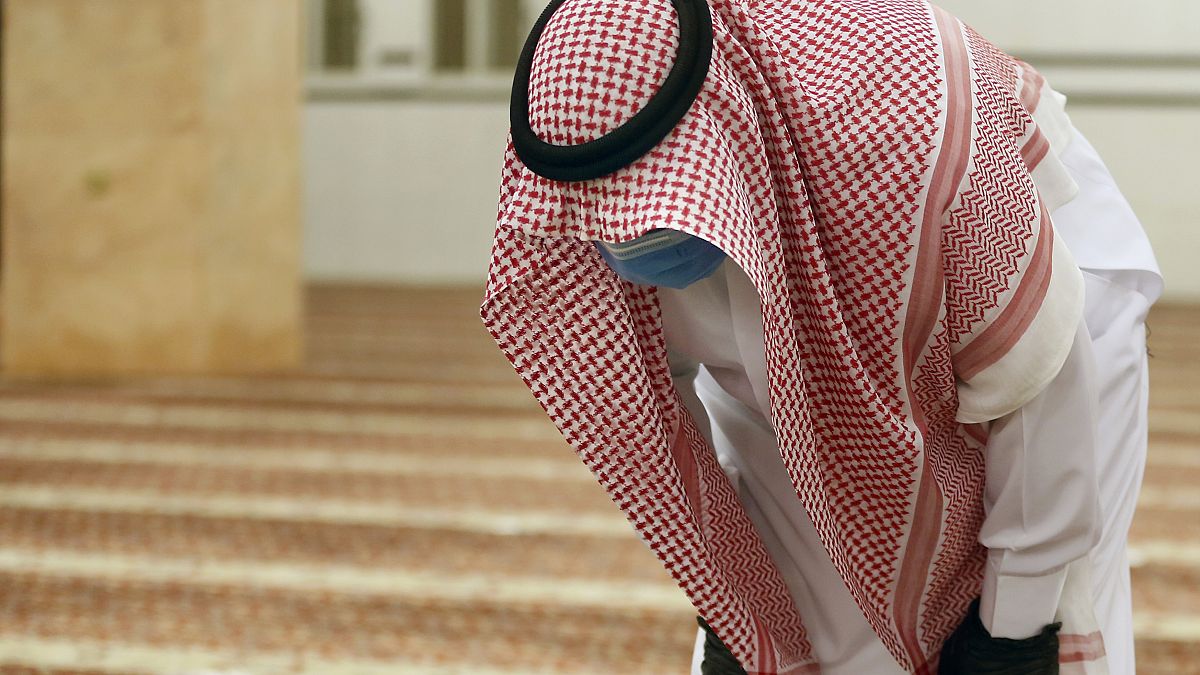 Suudi Arabistan'da eldiven ve maskesiyle camide namaz kılan bir kişi