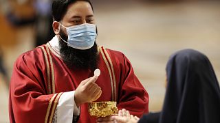 A deacon wearing a mask gives the communion to a nun during a Mass celebrated by Pope Francis in St. Peter's Basilica at the Vatican, Sunday, May 31, 2020