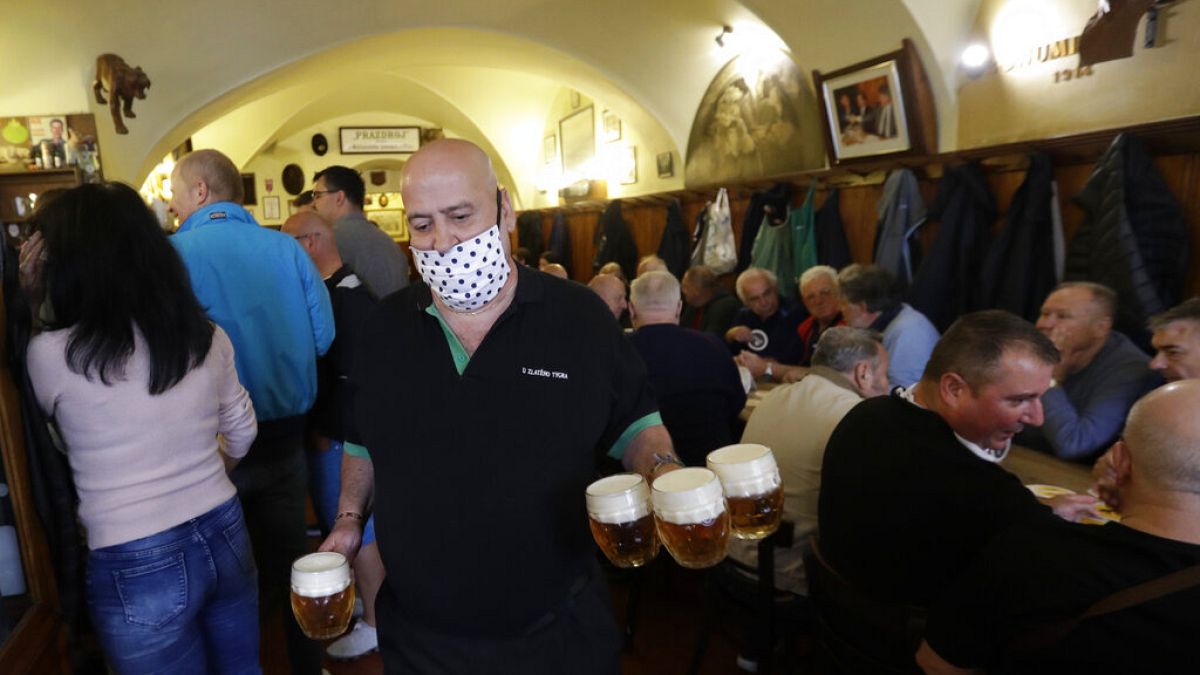 A waiter carries beer as a traditional beer pub opens in Prague, Czech Republic