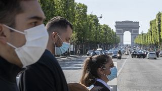 Des personnes portent des masques pour aider à freiner la propagation du coronavirus sur l'avenue des Champs-Élysées à Paris, le samedi 16 mai 2020.