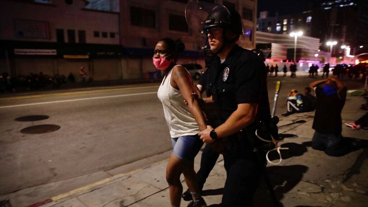 A police officer arrests a woman as protests over the death of George Floyd continue Sunday, May 31, 2020, in Los Angeles