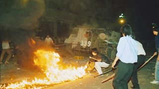 Student protesters put a barricade in front of a burning armored personnel carrier that rammed through student lines, June 4, 1989.