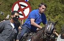 Brazil's President Jair Bolsonaro rides a horse greeting supporters outside the presidential palace in Brasilia, Brazil, Sunday, May 31, 2020. (AP Photo/Andre Borges)