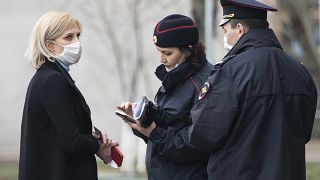 In this April 8, 2020, file photo, police officers check documents of a woman to ensure she is complying with a self-isolation regime due to coronavirus in Moscow, Russia