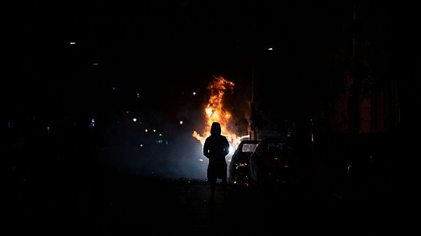 A demonstrator watches a car burn during protests over the death of George Floyd, near the White House in Washington, D.C. A demonstrator watches a car burn during protests over the death of George Floyd, near the White House in Washington, D.C.