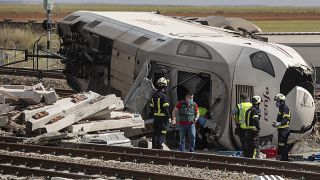 Bomberos y guardias civiles en la escena de un accidente después de que un tren de pasajeros de alta velocidad chocara con un coche en La Hiniesta
