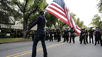 Un manifestante ondea una bandera ante policías en Los Ángeles