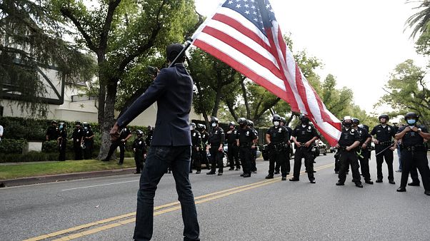 Un manifestante ondea una bandera ante policías en Los Ángeles Un manifestante ondea una bandera ante policías en Los Ángeles