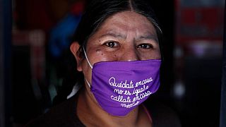 Una donna boliviana con una mascherina che recita in spagnolo: "Resta a casa. Non è la stessa cosa di 'stai zitto a casa' ".