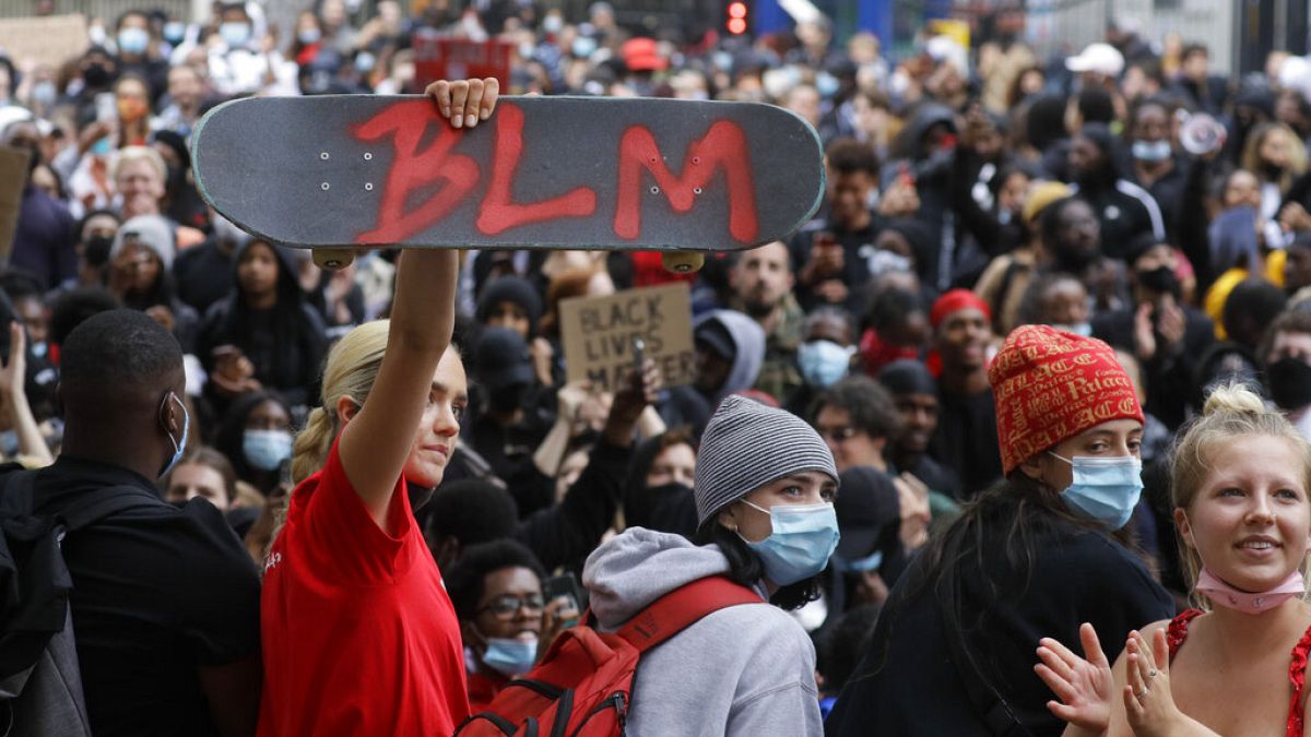 A protester holds up a skateboard with the Black Lives Matter initials in London, Wednesday, June 3, 2020 during a demonstration over the death of George Floyd.