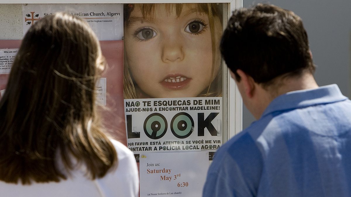 People look at a photograph of British missing girl Madeleine McCann on Friday May 2, 2008 at Praia da Luz beach, Lagos, Portugal