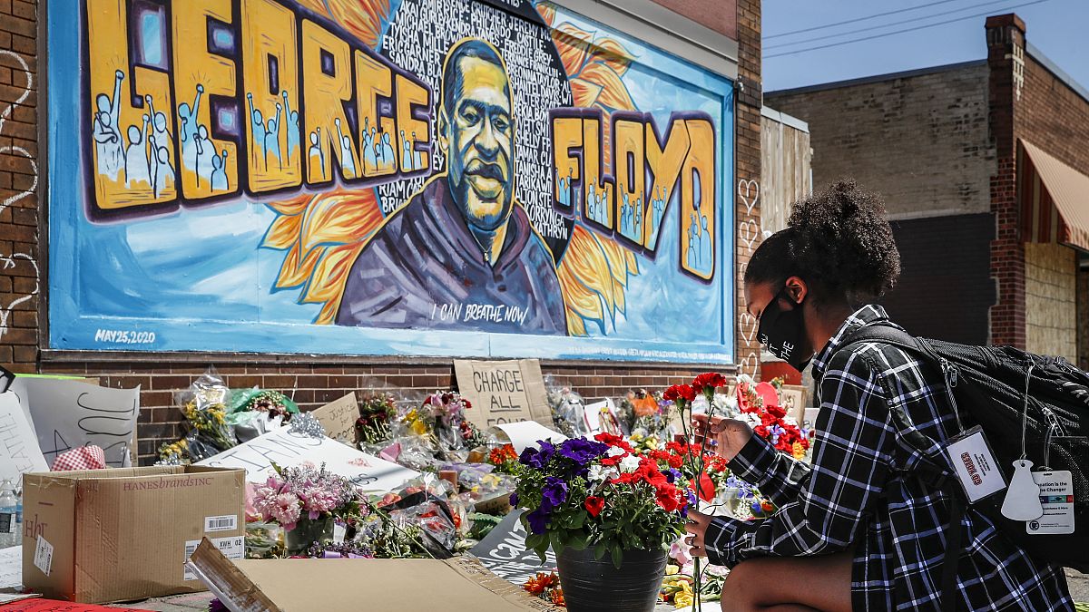 Malaysia Hammond, 19, places flowers at a memorial mural for George Floyd at the corner of Chicago Avenue and 38th Street, Sunday, May 31, 2020.