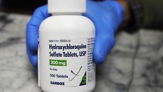 A pharmacist holds a bottle of the drug hydroxychloroquine in Oakland, Calif. in April 2020.