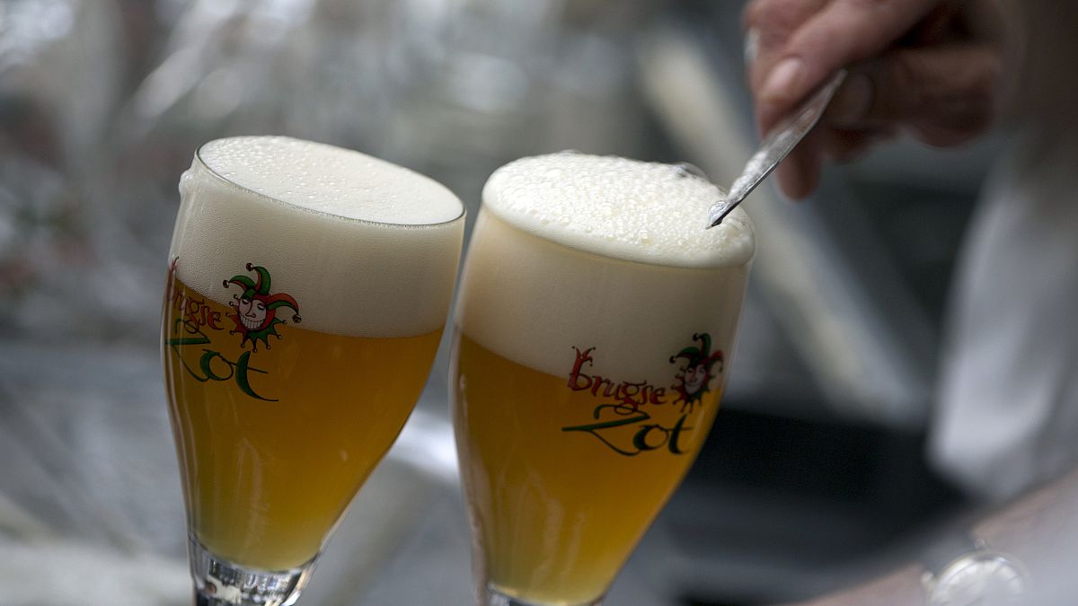 A worker scrapes the foam off of a glass of beer before serving, in Bruges, Belgium.