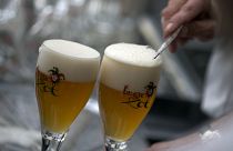 A worker scrapes the foam off of a glass of beer before serving, in Bruges, Belgium.