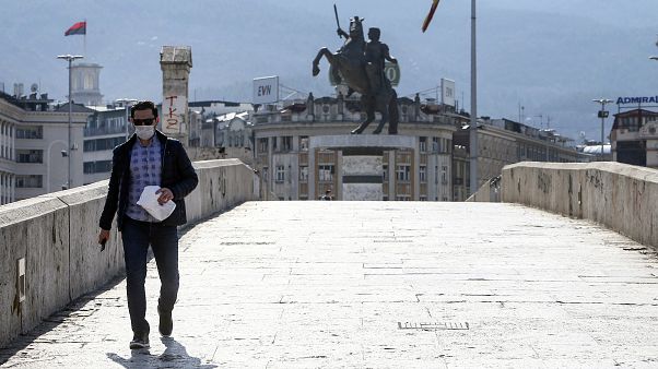 A man wearing a face mask and protective gloves walks across a usually crowded bridge in downtown Skopje A man wearing a face mask and protective gloves walks across a usually crowded bridge in downtown Skopje