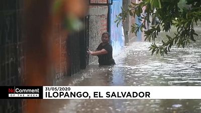 Una mujer avanza en medio de las inundaciones en El Salvador