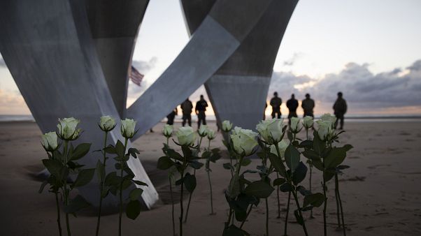 Men in a vintage US WWII uniforms stand behind flowers left at Les Braves monument after a D-Day 76th anniversary ceremony in Saint Laurent sur Mer, Normandy, France, Saturday Men in a vintage US WWII uniforms stand behind flowers left at Les Braves monument after a D-Day 76th anniversary ceremony in Saint Laurent sur Mer, Normandy, France, Saturday