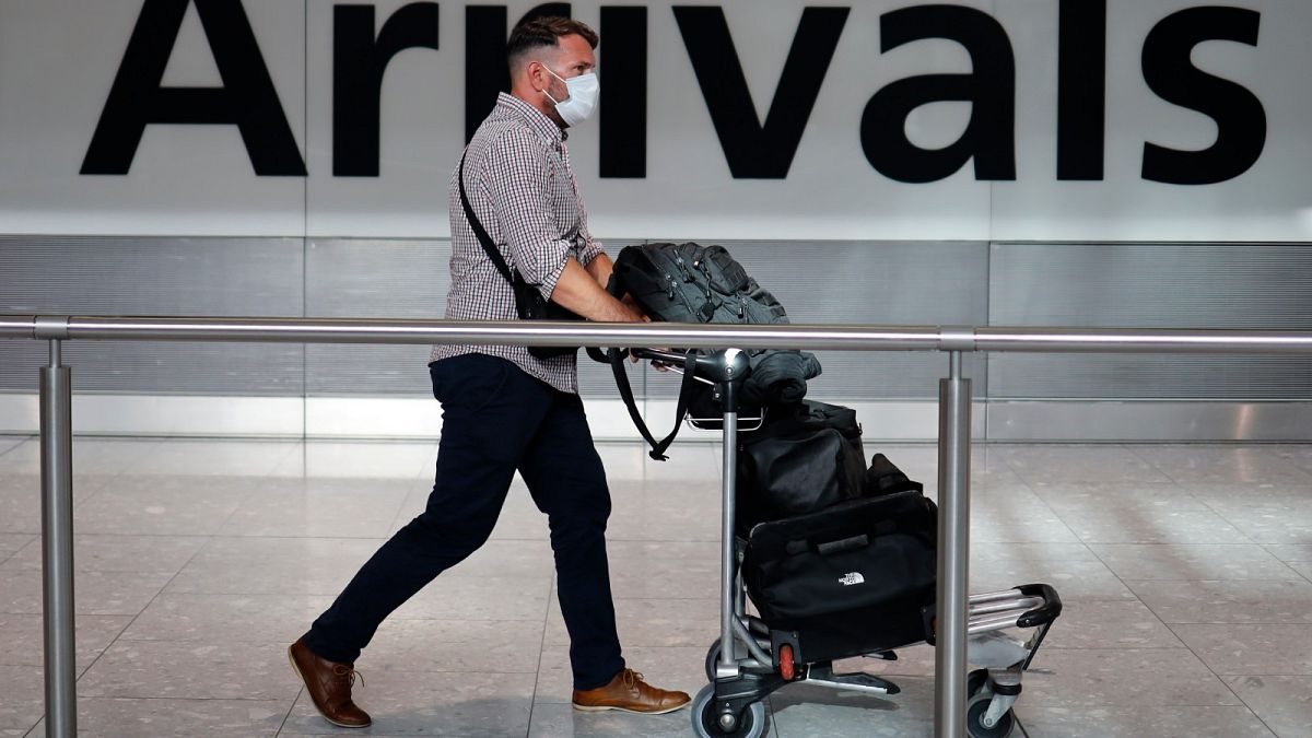 A passenger wearing a face mask as a precaution against the novel coronavirus arrive at Heathrow airport, west London, on May 22, 2020