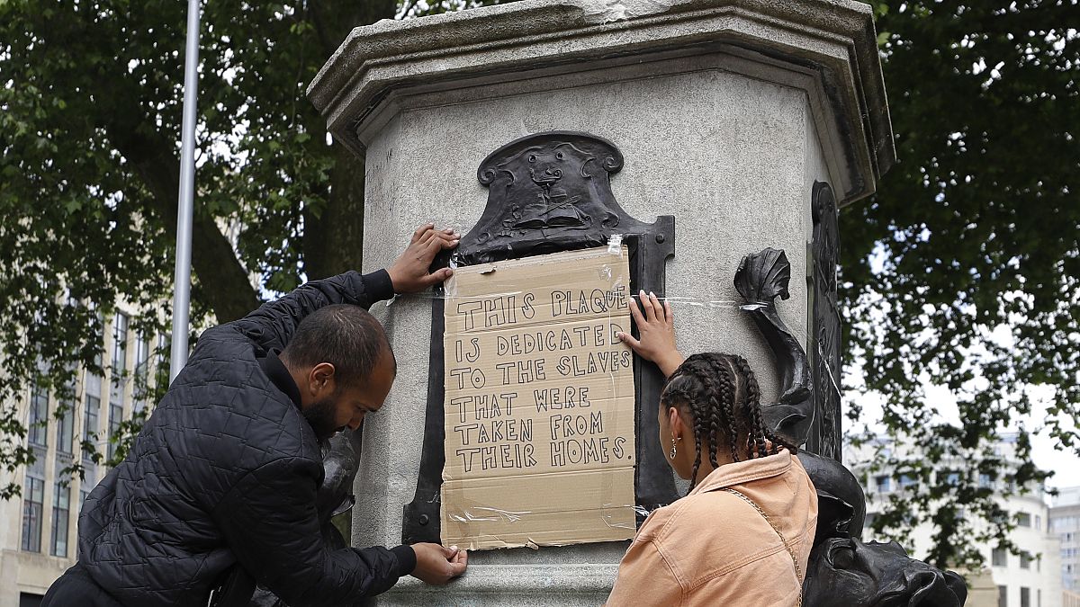 A banner is taped over the inscription on the pedestal of the toppled statue of Edward Colston in Bristol, England, Monday, June 8, 2020